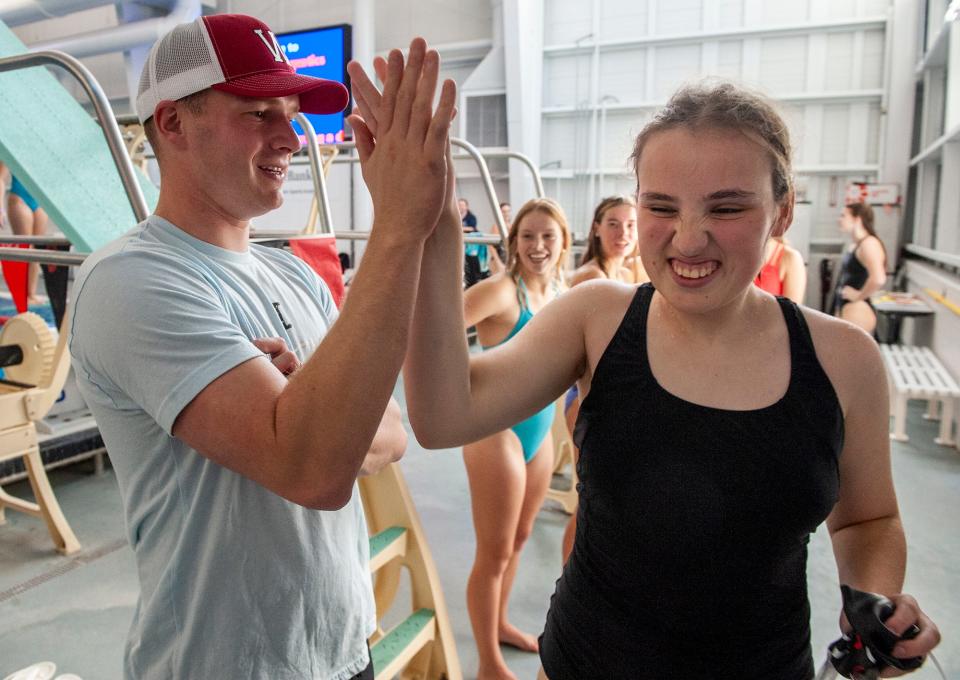 Wellesley High School girls swimming team coach Doug Curtin high fives senior Lily Kahrl at practice at the Boston Sports Institute, Oct. 4, 2023. Lily has a rare genetic disorder, STXBP1 encephalopathy. She competes in the 50-meter event.