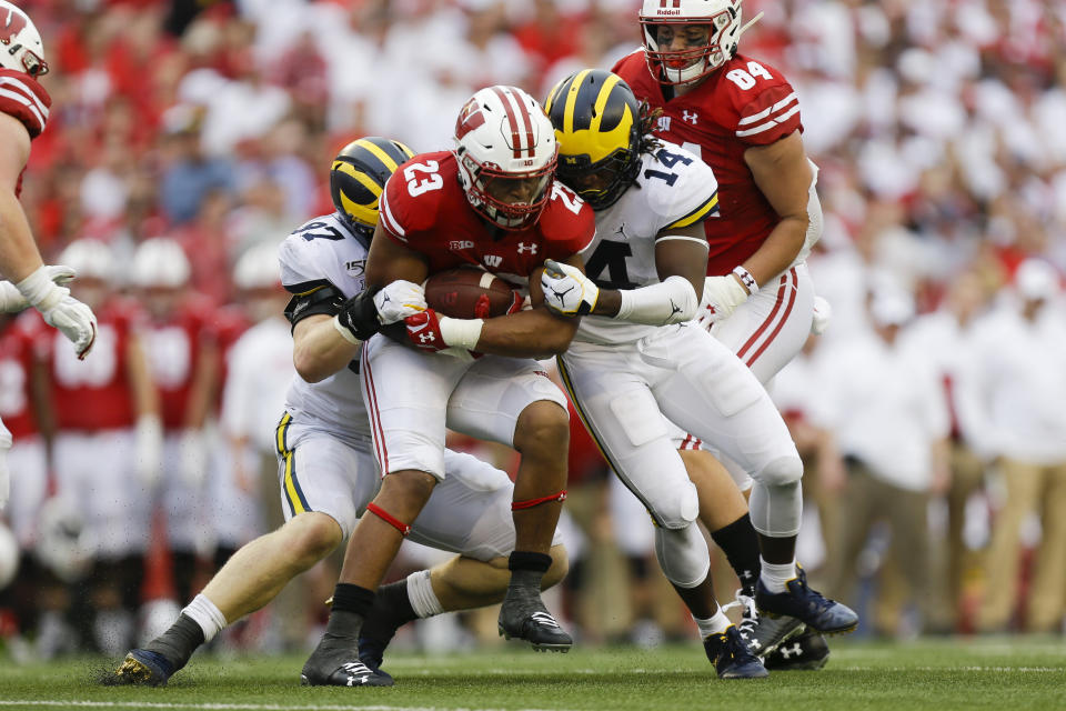 CORRECTS SCORE TO 35-14- Michigan defensive lineman Aidan Hutchinson, left, and defensive back Josh Metellus, right, tackle Wisconsin running back Jonathan Taylor, center, during the second half of an NCAA college football game Saturday, Sept. 21, 2019, in Madison, Wis. Wisconsin won 35-14. (AP Photo/Andy Manis)