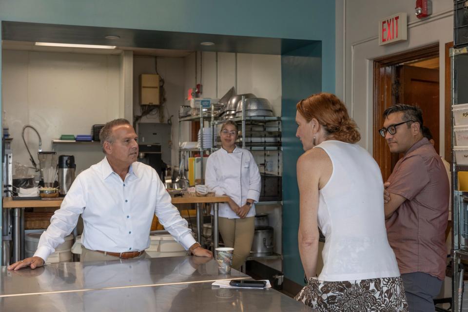 Rhode Island Foundation CEO David Cicilline talks with Shannon Carroll and Josha Riazi of the Genesis Center during a tour of the organization’s culinary training program as chef instructor Susie Peguero looks on.