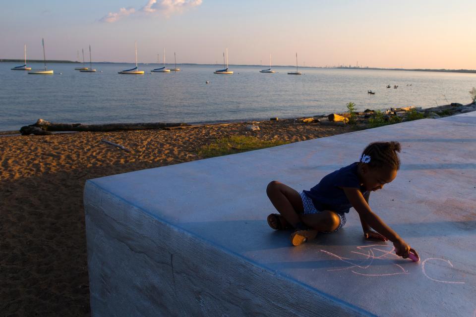 Latoya Simmons, left, and her daughter Malaya Sammons play with chalk as the sun sets over Battery Park in New Castle, De. 