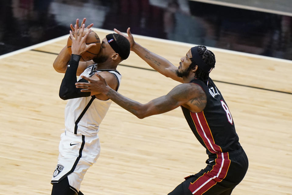 Brooklyn Nets guard Bruce Brown, left, loses control of the ball as he goes up for a shot against Miami Heat forward Trevor Ariza, right, during the second half of an NBA basketball game, Sunday, April 18, 2021, in Miami. (AP Photo/Wilfredo Lee)