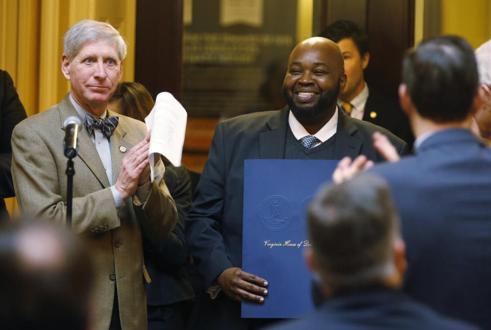 FILE - In this Jan. 24, 2019 file photo Virginia Teacher of the Year, Rodney Robinson, center right, smiles as he is honored on the floor of the Virginia House of Delegates as Del. Steven Landes, R-Augusta, left, applauds during the House session at the Capitol. Robinson was named Wednesday, April 24 as the 2019 National Teacher of the Year. He will spend the next year traveling around the country as an ambassador for education and an advocate for teachers and students. (AP Photo/Steve Helber)