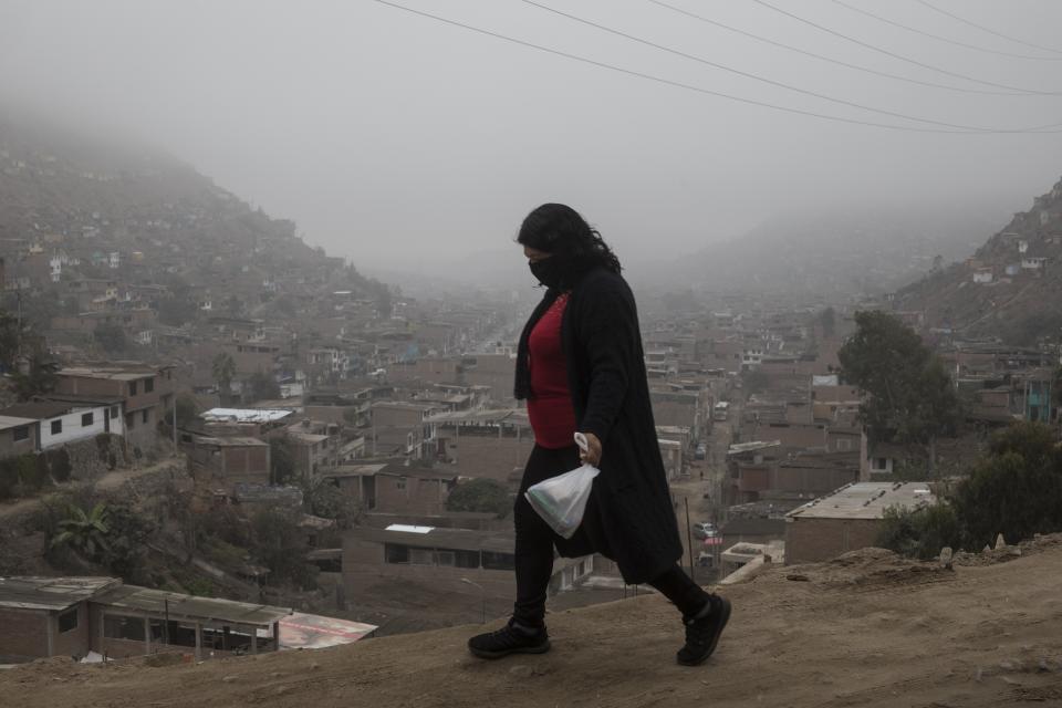 Una mujer con mascarilla contra el COVID-19 camina en el distrito de de Villa María del Triunfo, a las afueras de Lima, Perú, el martes 26 de mayo de 2020. (AP Foto/Rodrigo Abd)