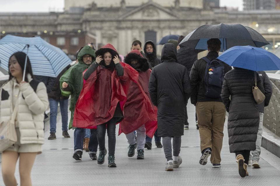 People brave the weather as they cross the Millennium Bridge in London (PA Wire)