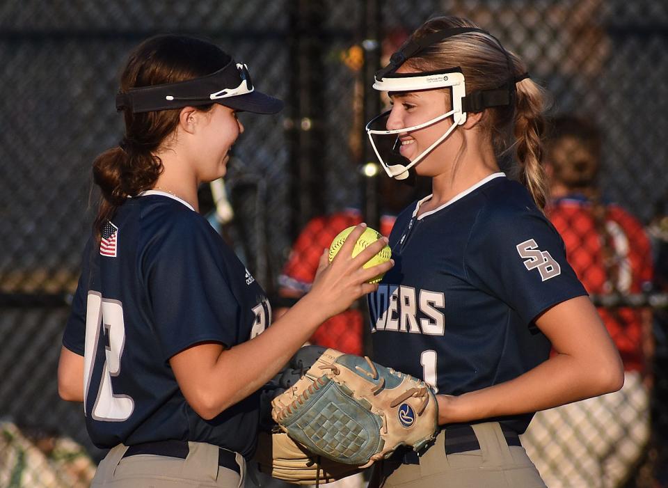 Raiders's Julia Costa and pitcher Tatum Swanson talk during Thursday's Division II state semifinal game.