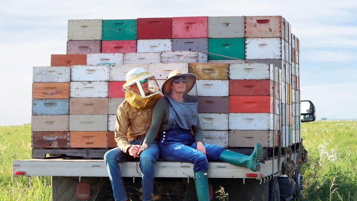 a couple of kids sitting on a truck with a large load of garbage