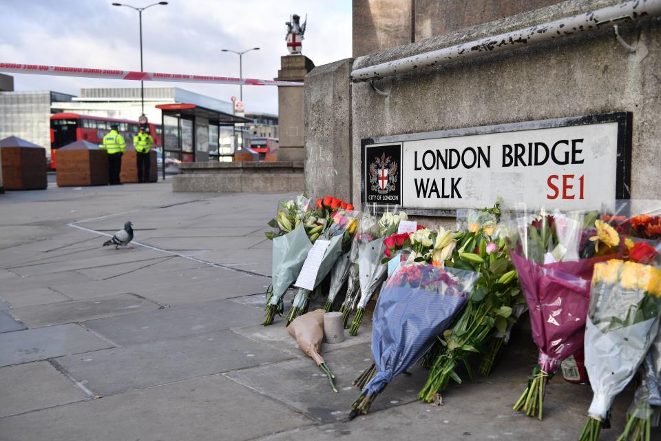 Police officers stand inside a cordon beside floral tributes left close to London Bridge in the City of London, on December 1, 2019, following the November 29 deadly terror incident. - Britain's Boris Johnson said on December 1 the security services were stepping up monitoring of convicted terrorists released early from prison, as the London Bridge attack became embroiled in the election campaign. (Photo by Ben STANSALL / AFP) (Photo by BEN STANSALL/AFP via Getty Images)