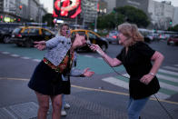 Ámbar Imoberdoff spurs on a passerby on a street corner where the 72-year-old retiree sings for tips, in downtown Buenos Aires, Argentina, Thursday, March 7, 2024. Thanks to her impromptu recitals, Imoberdoff, who is a widow and has no children, says she can earn up to $200 on a good night during the weekends. (AP Photo/Natacha Pisarenko)