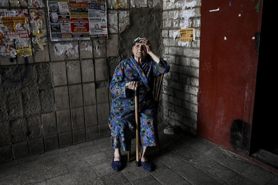 An eldery woman sits at the entrance of an apartment building in the city of Lysychansk at the eastern Ukrainian region of Donbas on 14 June (AFP via Getty Images)