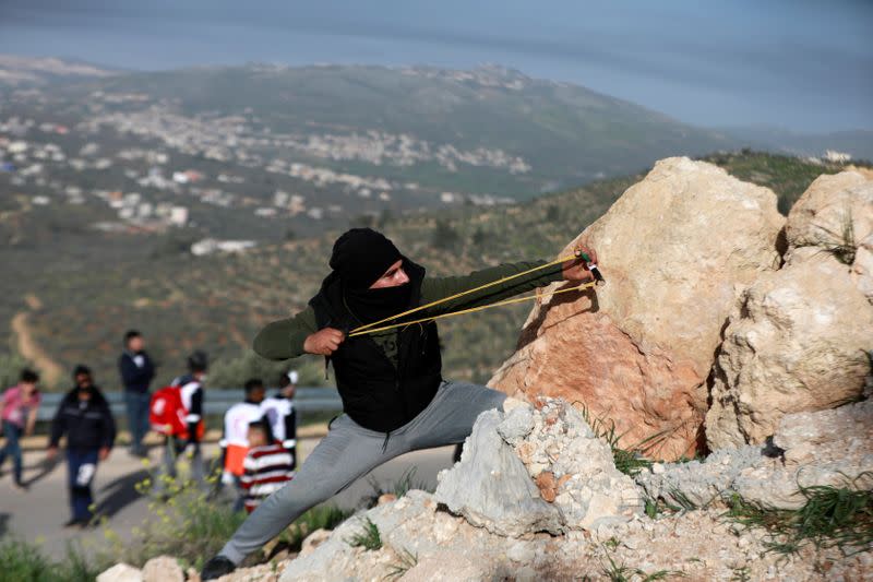 A Palestinian demonstrator uses a slingshot to hurl stones at Israeli forces during a protest against Israeli settlements, near the town of Beita in the Israeli-occupied West Bank