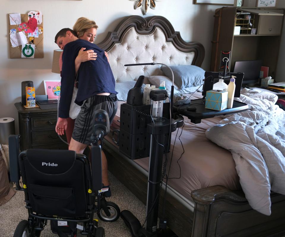 Cassi Tidwell moves her husband, Tyler, to the wheelchair from the bed in their Edmond home on April 5, 2021.