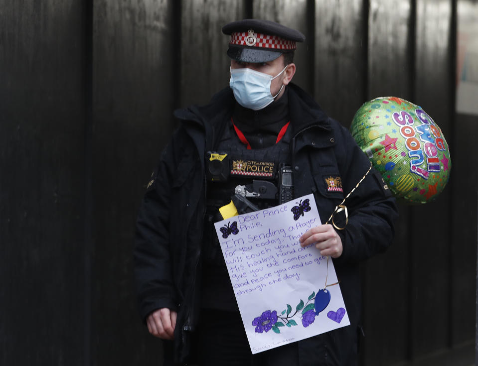 Un policía con una carta de buenos deseos y un globo fuera del Hospital St Bartholomew's donde se encuentra internado en príncipe Felipe en Londres el miércoles 3 de marzo de 2021. Felipe, el esposo de 99 años de la reina Isabel II, ha estado hospitalizado desde mediados de febrero. (Foto AP/Alastair Grant)