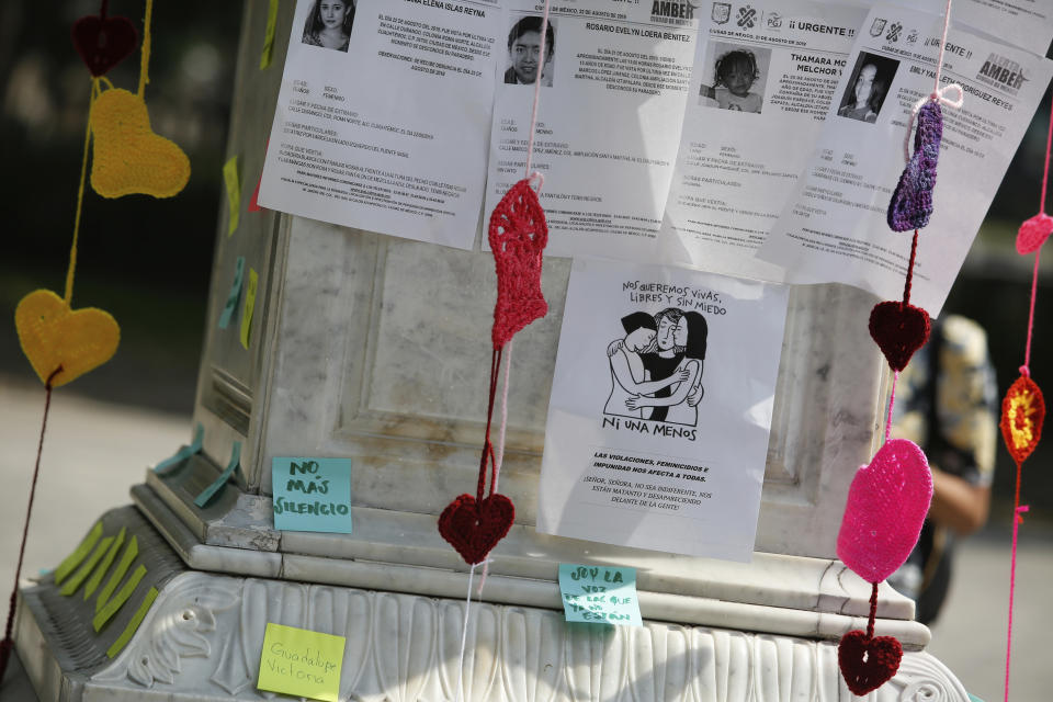 Posters with photographs of victims are posted on a plinth during a tribute for murdered women, in the Alameda park of Mexico City, Saturday, Aug. 24, 2019. A small group of women constructed a memorial made of hand-knit hearts. The knit-in on came on the heels of rowdy protests sparked by outrage over bungled investigations into alleged rapes of teenagers by local policemen. (AP Photo/Ginnette Riquelme)