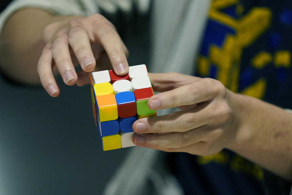 University of Michigan student Stanley Chapel explains how he studies the Rubik's Cube before solving the cube while blindfolded, Wednesday, Nov. 23, 2022, in Ann Arbor, Mich. Stanley is one of the world's foremost "speedcubers," a person capable of quickly solving a Rubik's Cube. He also is an accomplished violinist. Chapel says the two fields aren't as different as one might think. Chapel has certain inherent abilities -- he is capable of remembering and applying thousands of algorithms to solve a Rubik's Cube and performing one of Johann Sebastian Bach's violin sonatas from memory. (AP Photo/Carlos Osorio)