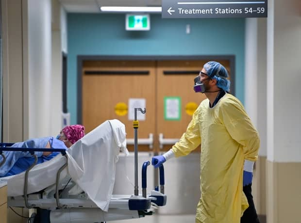 A health-care worker wearing PPE transports a patient in the dialysis unit at the Humber River Hospital during the COVID-19 pandemic in Toronto on Wednesday, December 9, 2020.  (Nathan Denette/The Canadian Press - image credit)