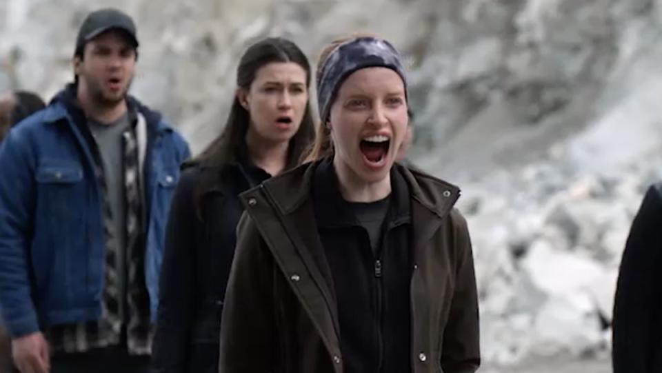 Two women and a man stand outside screaming