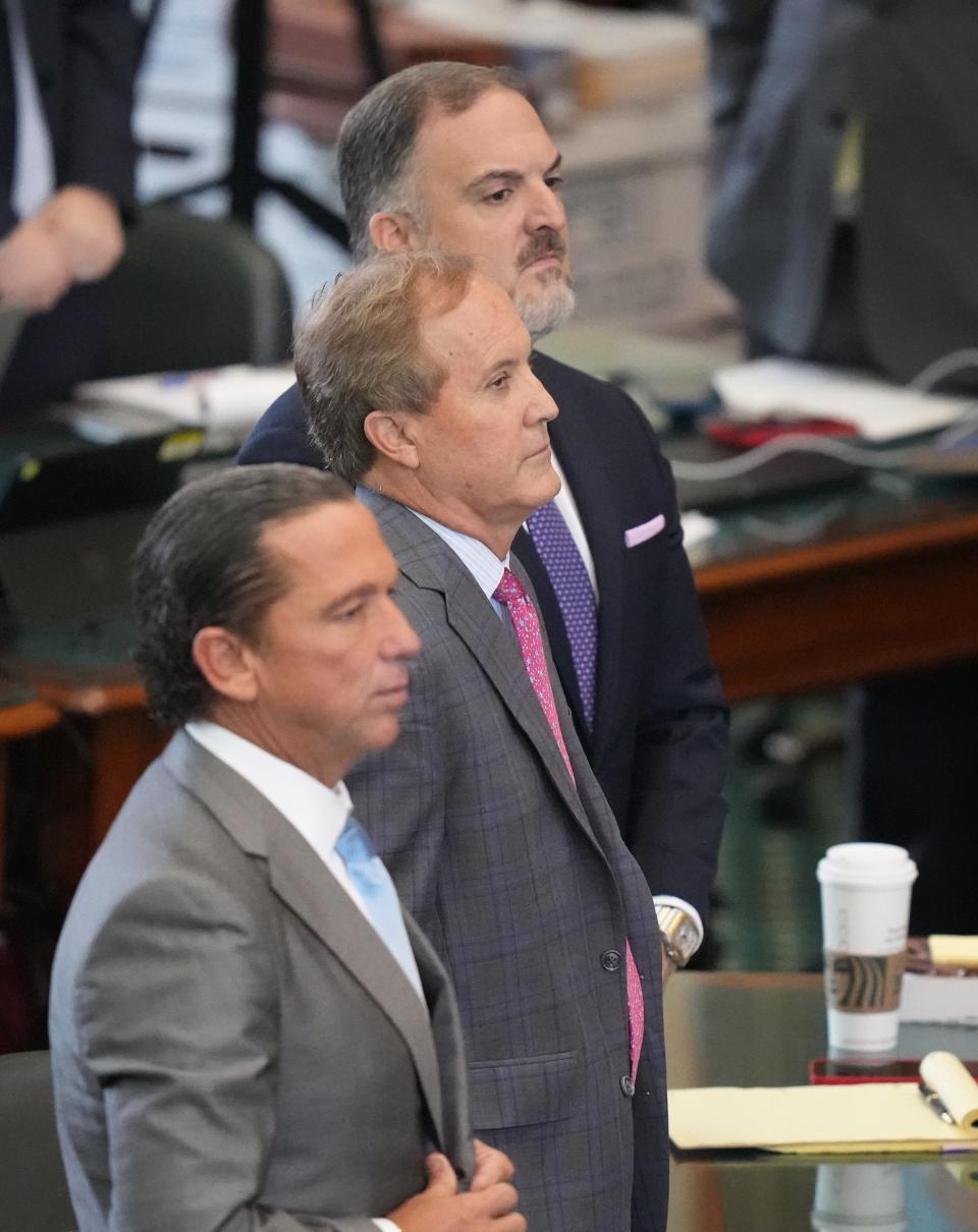 Attorney General Ken Paxton, middle, and his attorneys Tony Buzbee, left, and Mitch Little stand as senators arrive Friday for his impeachment trial at the Capitol.