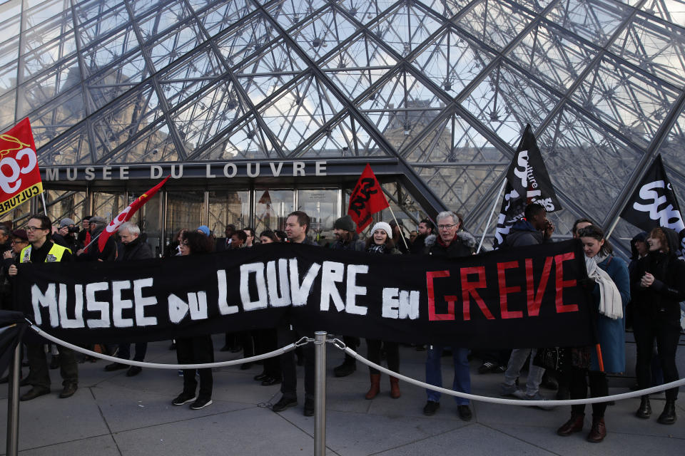 Striking employees demonstrate with a banner reading "Louvre museum on strike" outside the Louvre museum, Friday, Jan. 17, 2020 in Paris. Paris' Louvre museum was closed Friday as dozens of protesters blocked the entrance to denounce the French government's plans to overhaul the pension system. (AP Photo/Francois Mori)