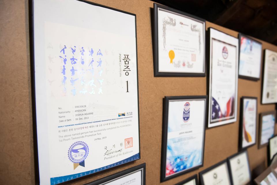 Letters of achievement, including his 1st degree black belt certificate (far left), decorate a wall inside Joshua Aguirre's home training space in Lebanon. When Joshua passed his 2nd degree black belt test at seven years old, he became the youngest person in the world to do so.