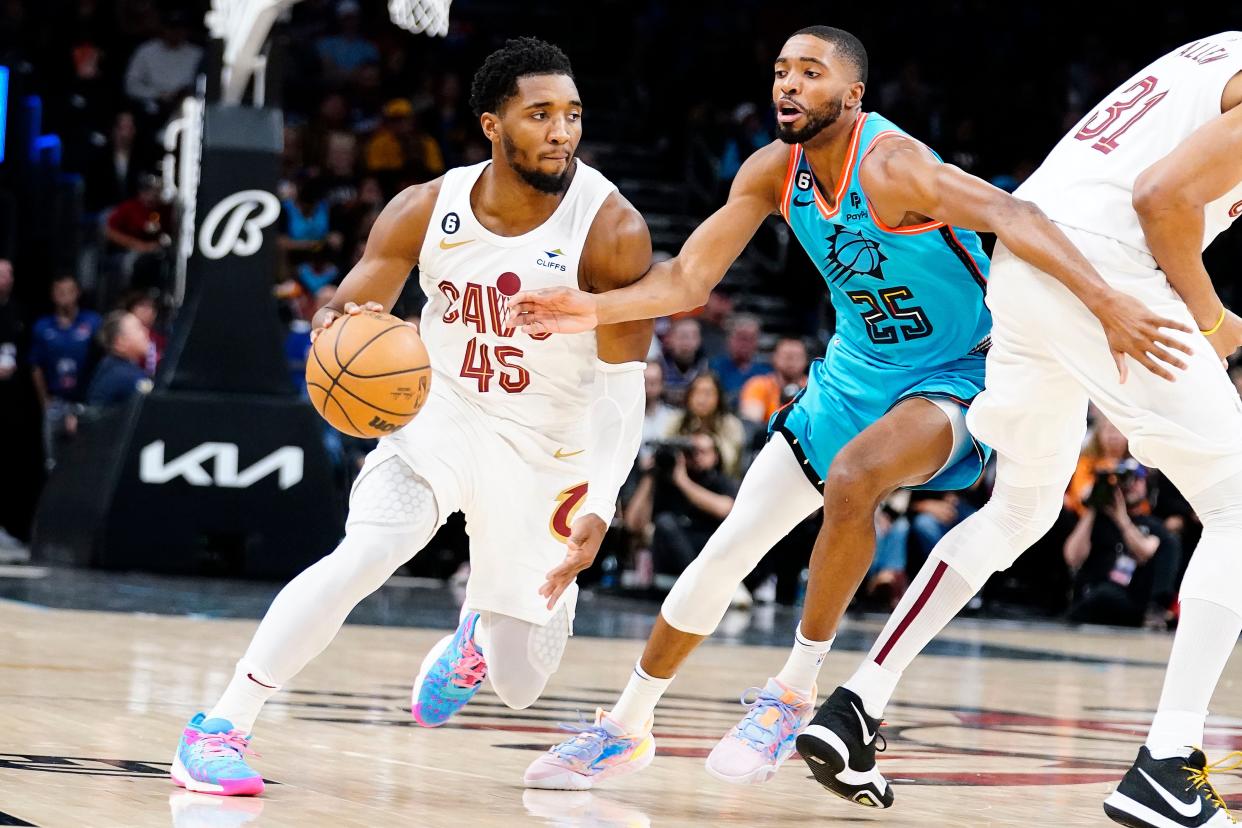 Cleveland Cavaliers' Donovan Mitchell (45) drives around Phoenix Suns' Mikel Bridges (25) during the first half of an NBA basketball game in Phoenix, Sunday, Jan. 8, 2023. (AP Photo/Darryl Webb)