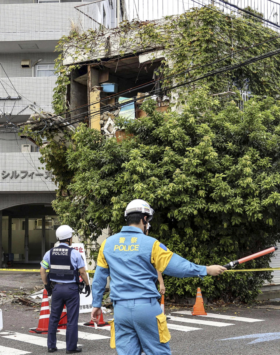 Image : Des policiers se tiennent à l'extérieur d'un bâtiment endommagé après un tremblement de terre à Miyazaki, dans l'ouest du Japon (Kyodo News via fichier AP)