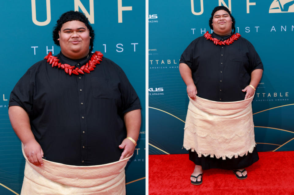 Man in black shirt and traditional wrap with necklace, posing on the red carpet