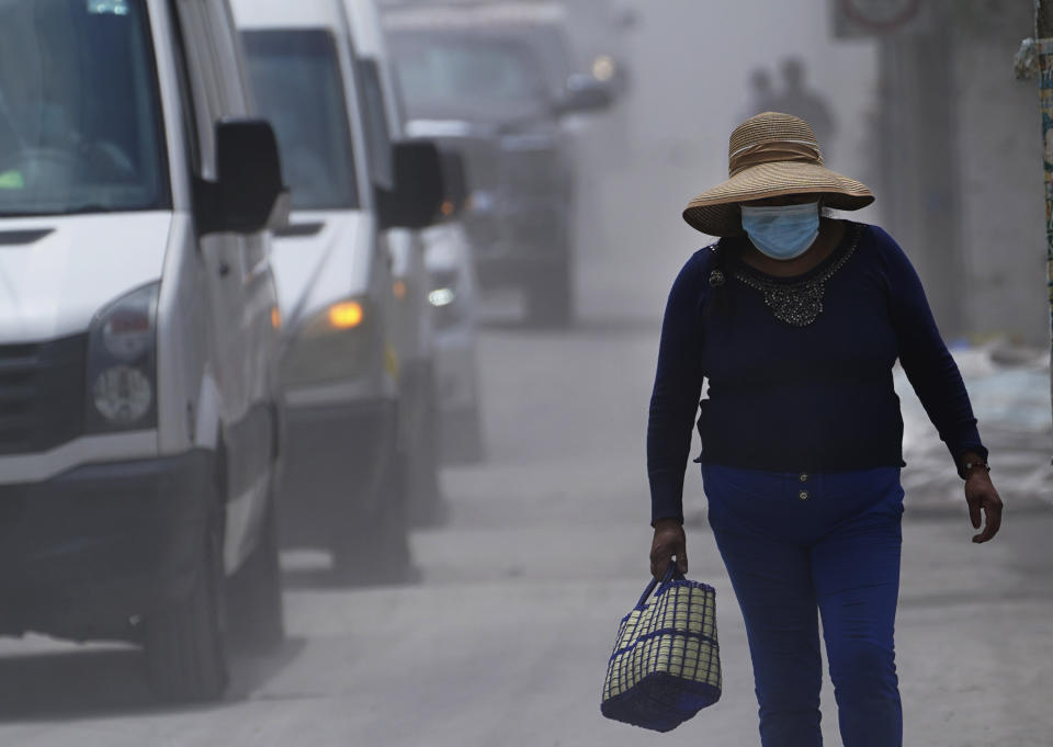 A woman walks on the ash-covered streets from the Popocatepetl volcano in Santiago Xalitzintla, Mexico, Monday, May 22, 2023. The volcano´s activity has increased over the past week. Evacuations have not been ordered, but authorities are preparing for that scenario and telling people to stay out of 7.5-mile (12-kilometer) radius around the peak. (AP Photo/Marco Ugarte)