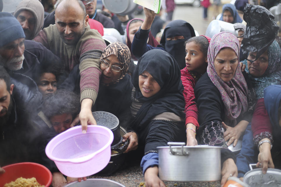 Palestinians line up for free food distribution during the ongoing Israeli air and ground offensive in Khan Younis, Gaza Strip, Friday, Feb. 2, 2024. (AP Photo/Hatem Ali)