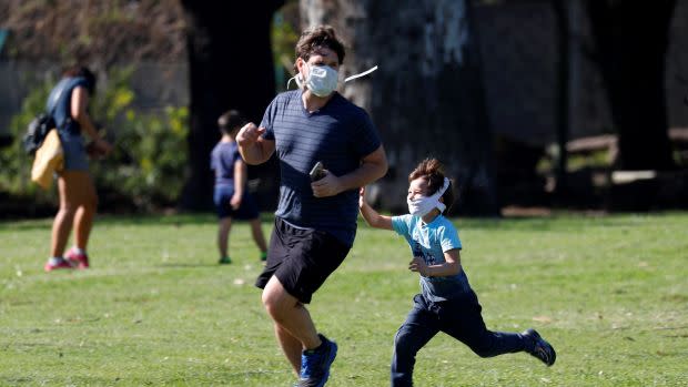 A father and his son wearing face masks play tag in a park after restrictions were partially lifted for children in the city of Buenos Aires during the coronavirus disease (COVID-19) outbreak, Argentina