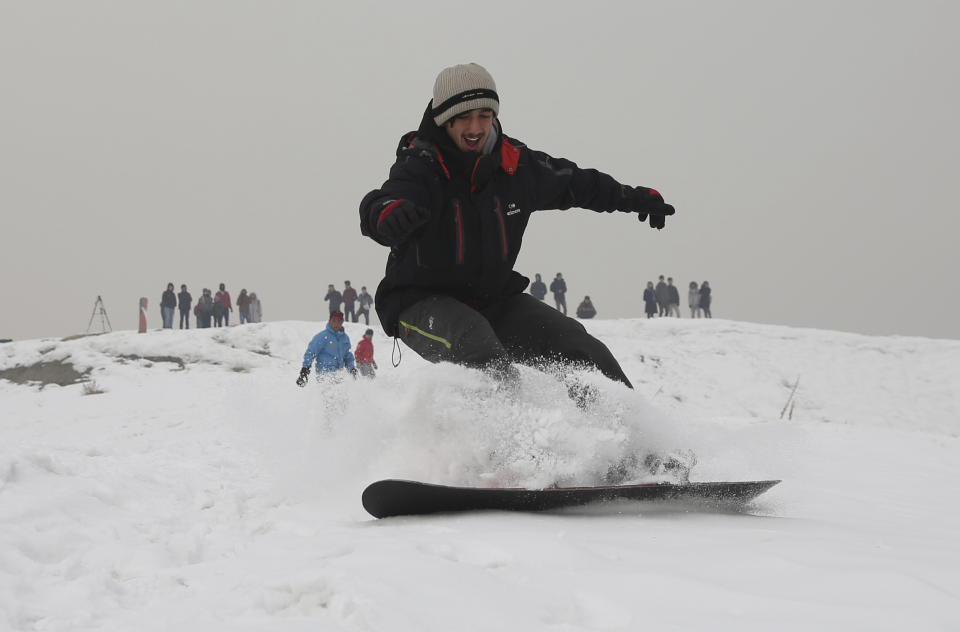 In this Friday, Jan. 24, 2020 photo, Ahmad Sorush, 22, a member of the Afghanistan Snowboarding Federation practices on the outskirts of Kabul, Afghanistan. A handful of federation members hit the slopes outside Kabul each weekend, usually with around a dozen male and female students and plenty of spectators. They come for the free training on the snowy hillside west of the capital, often shrouded in pale grey mist. (AP Photo/Rahmat Gul)