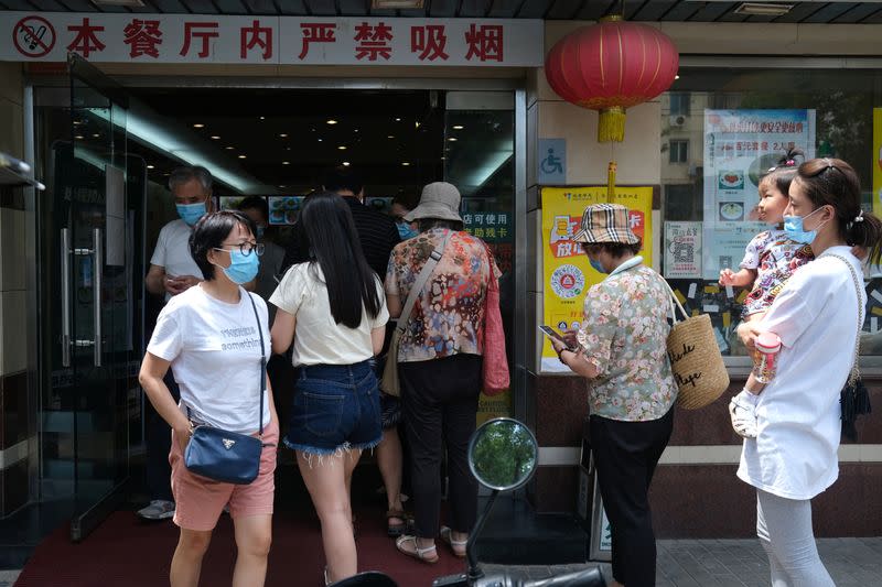 Customers wearing face masks line up to enter a restaurant, following the coronavirus disease (COVID-19) outbreak, in Beijing