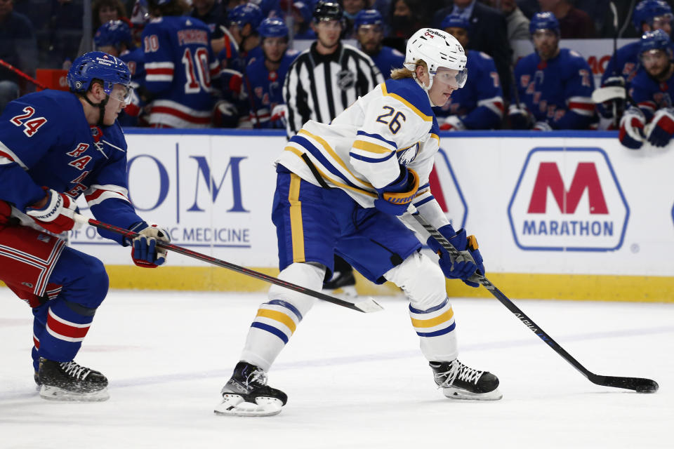 Buffalo Sabres defenseman Rasmus Dahlin (26) moves the puck past New York Rangers right wing Kaapo Kakko (24) during the first period of an NHL hockey game Friday, Dec. 10, 2021, in Buffalo, N.Y. (AP Photo/Jeffrey T. Barnes)