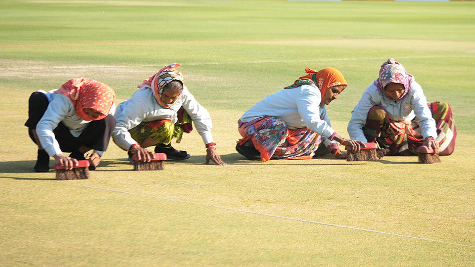 Four women, pictured here scrubbing the pitch with hand-held brushes at the Saurashtra Cricket Association Stadium in Rajkot.