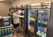 In this provided by Anthony Love, Hunter Weertman, 16, left, works alongside a fellow student to stock the refrigerator in the student-led free grocery store at Linda Tutt High School on Nov. 20, 2020, in Sanger, Texas. The store provides food, toiletries and household items to students, faculty and community members in need. (Anthony Love via AP)