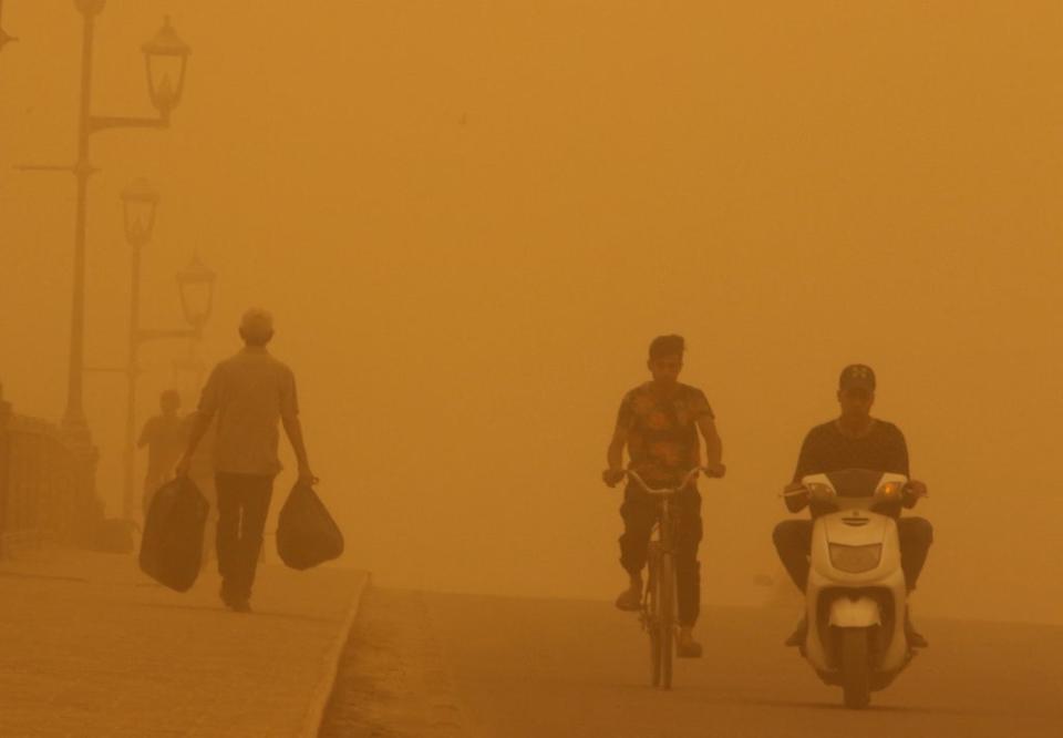 People cross a bridge during a sandstorm in Baghdad on 16 May 2022 (Reuters)