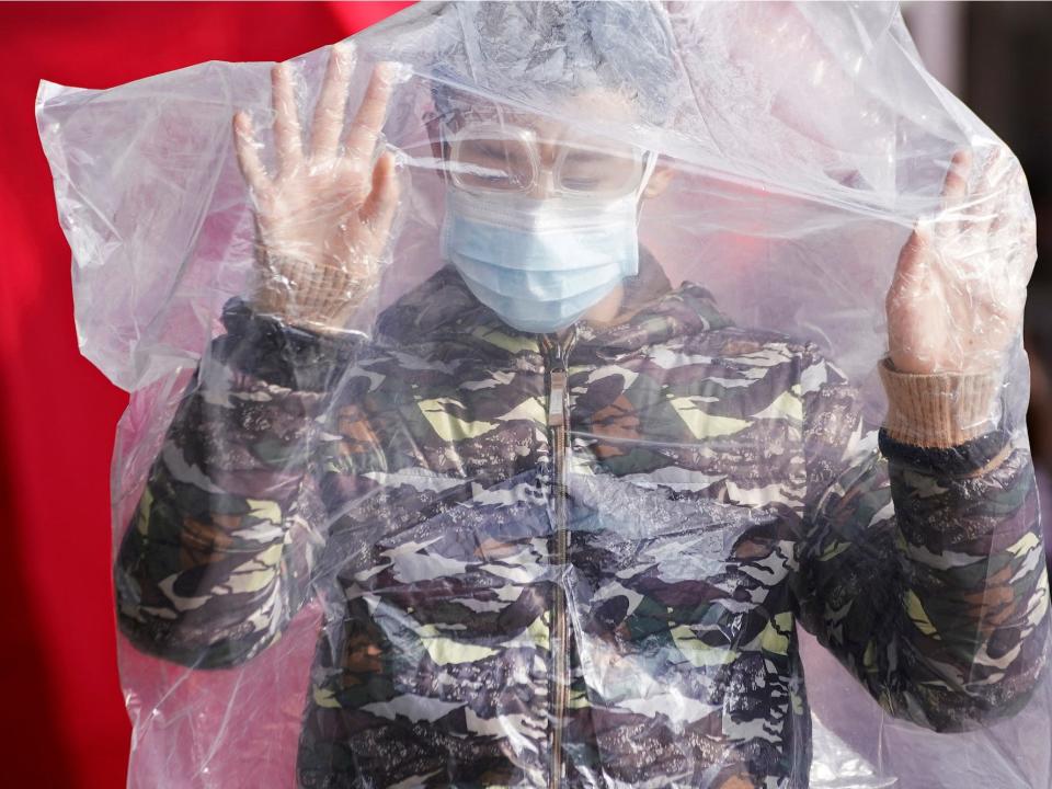 A passengers wearing a mask and covered in a plastic cape in Shanghai.JPG