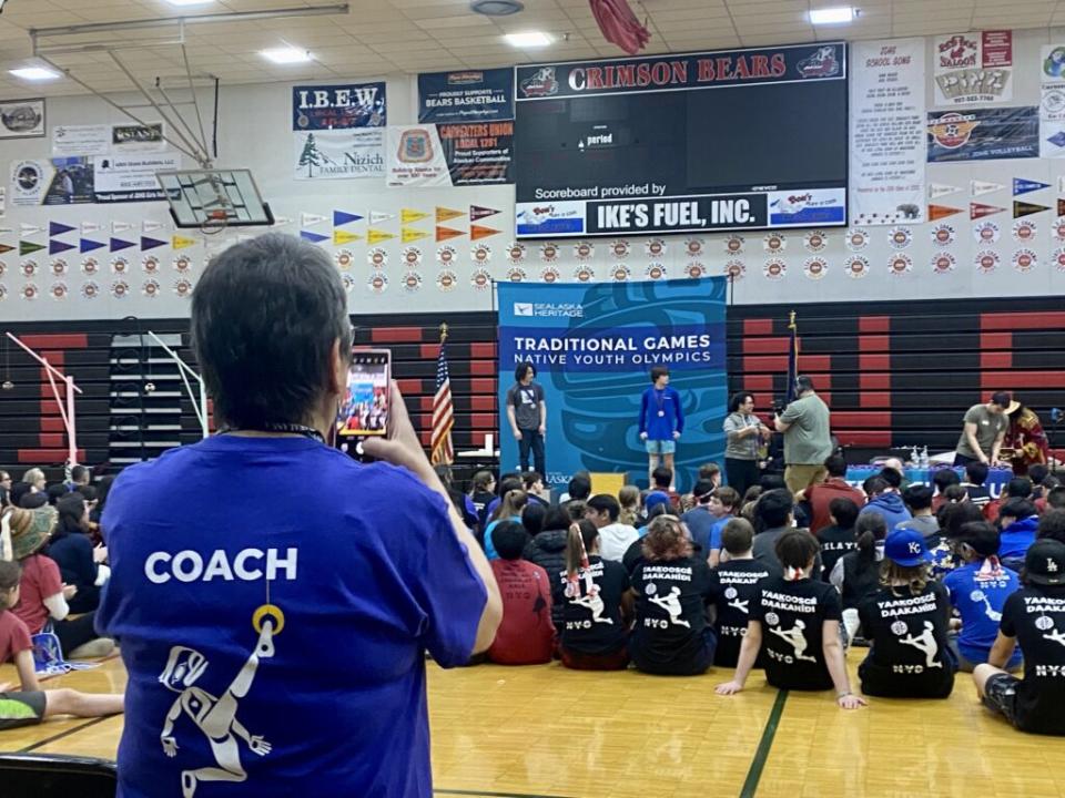 Self proclaimed proud grandma and coach Carol Hull snaps pictures as her grandson and his teammates win medals at the Traditional Games in Juneau on April 7, 2024. (Photo by Claire Stremple/Alaska Beacon)