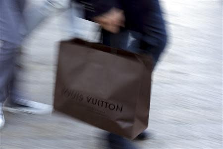 A man walks with a Louis Vuitton shopping bag as he leaves a Louis Vuitton store in Paris September 24, 2013. REUTERS/Philippe Wojazer