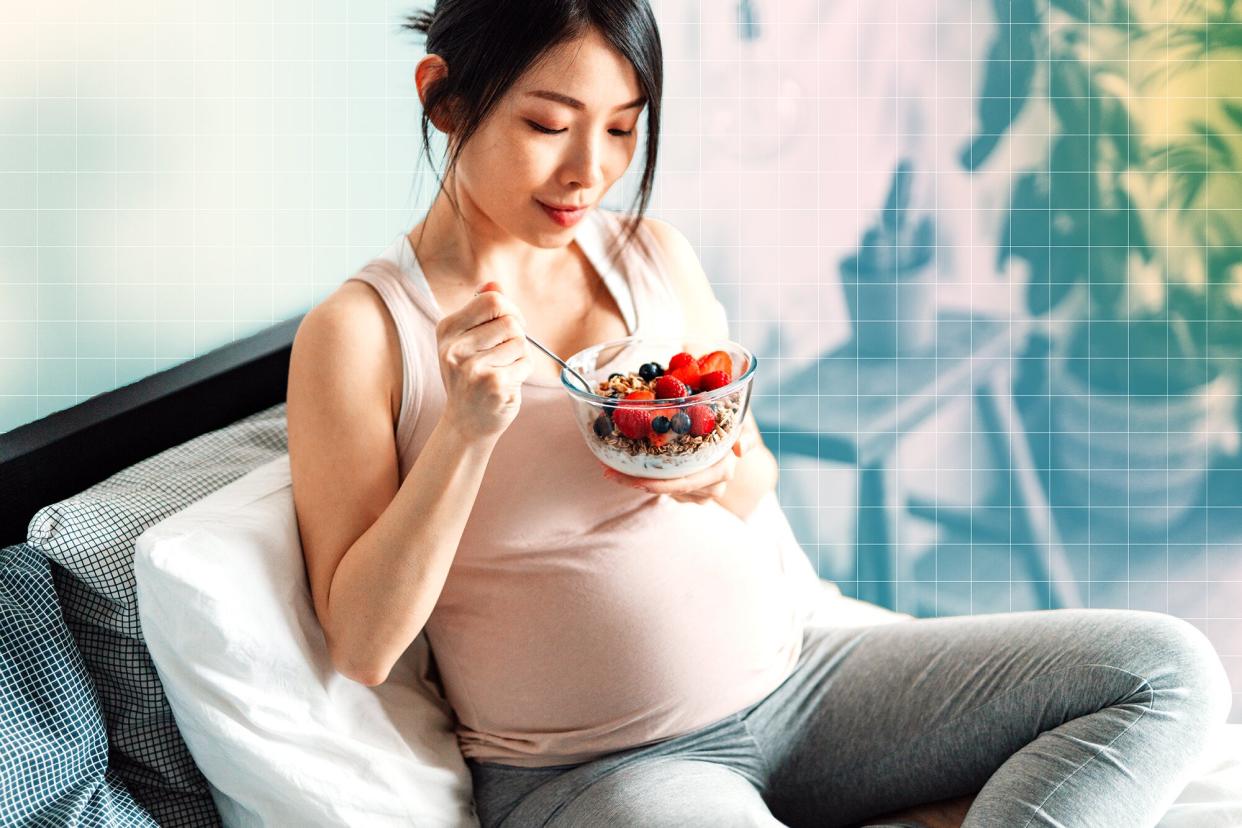 A pregnant woman eating while sitting on a couch