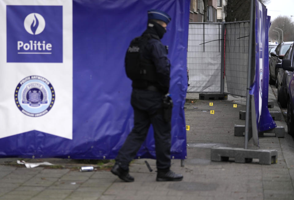 A police officer walks in front of forensic markers after a shooting in Merksem district of Antwerp, Belgium, Tuesday, Jan. 10, 2023. Antwerp itself has been hit by two dozen grenade attacks, fires and small bombs that have often been linked to gangs trying to carve up the thriving cocaine trade that uses the north Belgian harbor as a port of call. Compounding the increasing threat in a city better known for painter Peter-Paul Rubens and its famed fashion school was Monday evening's fatal shooting of an 11 year-old-girl, likely an unwitting victim of the drug war. (AP Photo/Virginia Mayo)