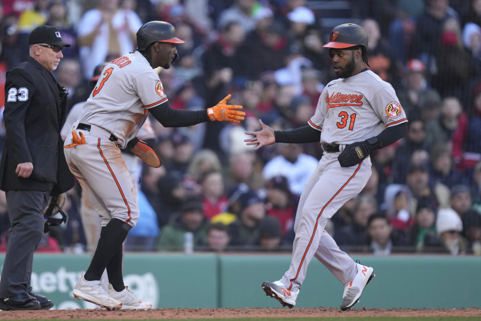 Baltimore Orioles' Cedric Mullins (31) and Jorge Mateo (3) celebrate after scoring on a single by Adley Rutschman during the fifth inning of an opening day baseball game against the Boston Red Sox at Fenway Park, Thursday, March 30, 2023, in Boston. (AP Photo/Charles Krupa)