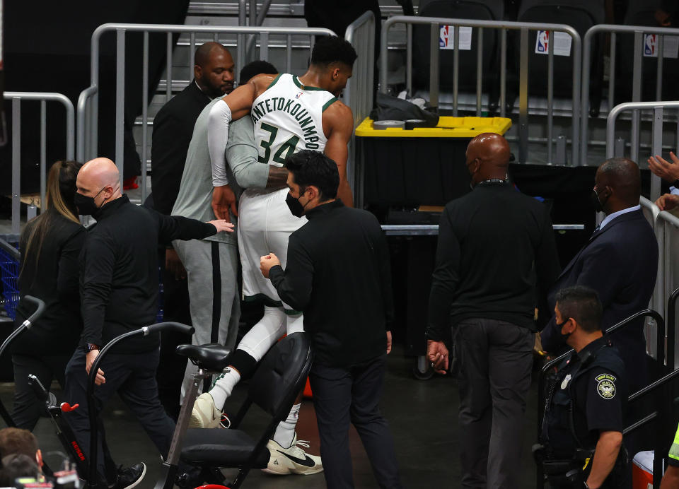 Giannis Antetokounmpo is helped off the court after a knee injury. (Photo by Kevin C. Cox/Getty Images)