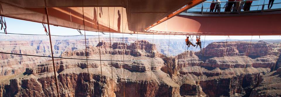 In this Tuesday, March, 25, 2014 photo provided by Abseilon USA via AZ Photos, technicians dangle from a series of ropes before polishing the underside glass at Grand Canyon Skywalk in Hualapai Reservation, Ariz. The more than 40 panes of glass underneath the horseshoe-shaped bridge on the Hualapai reservation aren’t easily accessible. The structure juts out 70 feet from the edge of the Grand Canyon, offering visitors a view of the Colorado River 4,000 feet below. (AP Photos/Abseilon USA, AZ Photos, George Walsh)