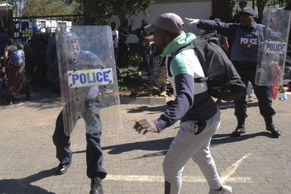 Refugees, mostly from the Democratic Republic of Congo, face off with South African Police officers, at the United Nations High Commissioner for Refugees (UNHCR) compound in Pretoria, South Africa, Friday, Nov. 15, 2019. Police removed about 150 refugees who the United Nations refugee agency says forced their way into its compound while protesting recent anti-immigrant attacks. (AP Photo/Elna Schütz)