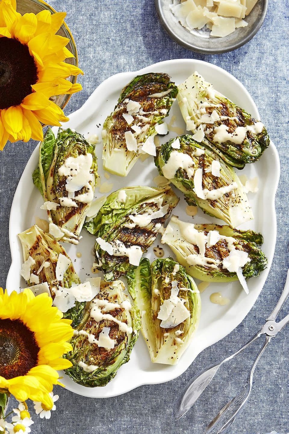 charred gem lettuce with almond caesar dressing on an oval white serving plate