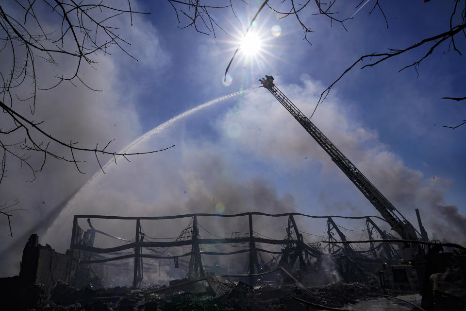 Firefighters pour water on an industrial fire in Richmond, Ind., Thursday, April 13, 2023. Multiple fires that began burning Tuesday afternoon were still burning within about 14 acres of various types of plastics stored inside and outside buildings at the former factory site. (AP Photo/Michael Conroy)