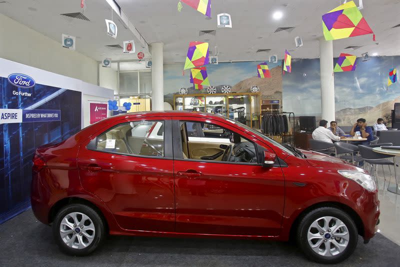 FILE PHOTO: Customers sit near Ford's new Figo Aspire car on display at a showroom in New Delhi