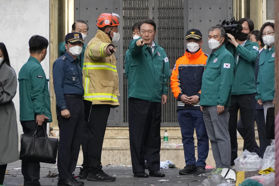 South Korean President Yoon Suk Yeol, center, is briefed at the scene where dozens of people died and were injured in Seoul, South Korea, Sunday, Oct. 30, 2022, after a mass of mostly young people celebrating Halloween festivities became trapped and crushed as the crowd surged into a narrow alley. (AP Photo/Lee Jin-man)