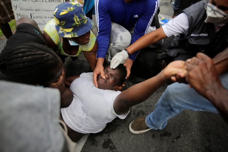 A migrant is helped by fellow migrants from Africa, Cuba and Haiti, who are stranded in Honduras after borders were closed due to the coronavirus (COVID-19) pandemic, while convulsing during a trek northward in an attempt to reach the U.S., in Choluteca