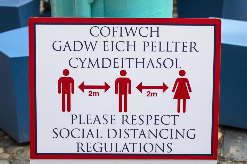 Close-up of a social distancing sign in the village of Portmeirion in North Wales, UK - in both the Welsh and English languages.